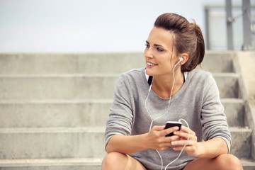 Happy Female Athlete Listening to Music While Resting - obrazy, fototapety, plakaty