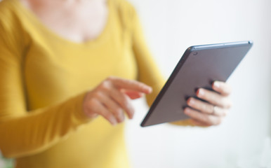 Woman in yellow using a digital tablet