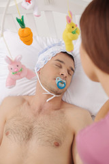 Big baby in bed. Top view of infant adult man lying on the baby