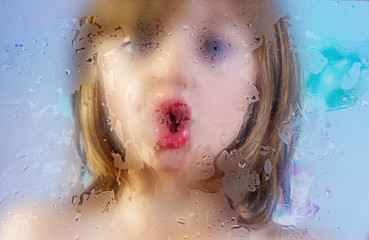girl behind a dewy glass in a shower