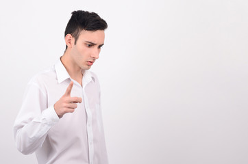Young man in white shirt looking down and pointing the finger.