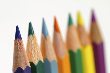 seven colored pencils in a row, with selective focus on the left