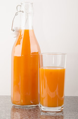 carrot juice in a glass and a bottle