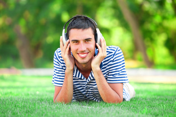 Handsome young man with headphones at green grass