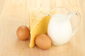 Big piece of cheese, glass jug with milk