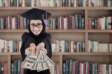 Female graduate holding money at library