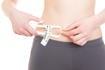 Woman measuring her body fat on adbomen using caliper