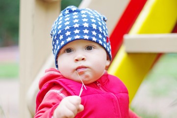 portrait of lovely baby chewing straw on playground