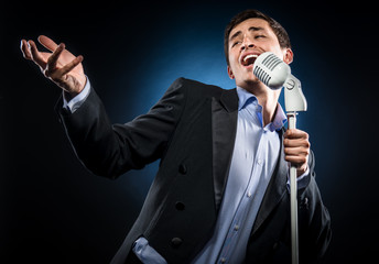 Naklejka premium Man in elegant black jacket and blue shirt singing