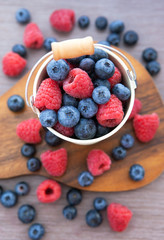 Fresh blueberries and raspberries in a  bucket