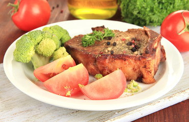 Piece of fried meat on plate on wooden table close-up