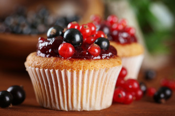 Tasty muffins with berries on wooden table