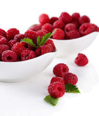 Ripe sweet raspberries in bowls, isolated on white