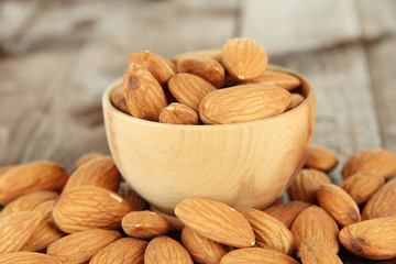 Almond in wooden bowl, on wooden background