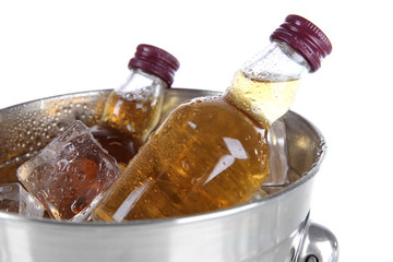Minibar bottles in bucket with ice cubes, isolated on white
