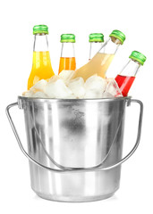 Bottles with tasty drinks in bucket with ice cubes, isolated