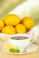 Cup of tea with lemon on table on light background