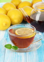 Cup of tea with lemon on table on blue background