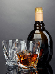 Glass of liquor with bottle, on dark background