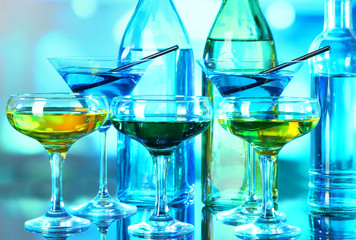 Glasses of cocktails on bright background