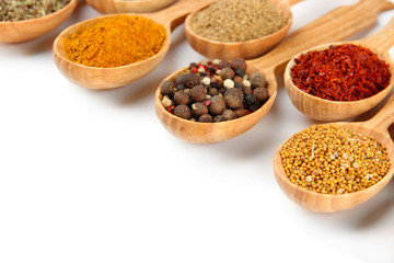 Assortment of spices in wooden spoons, isolated on white