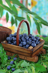 Blueberries in wooden basket on grass on nature background