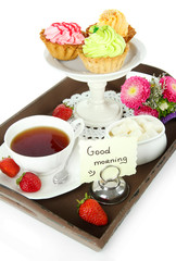Cup of tea with cakes on wooden tray isolated on white