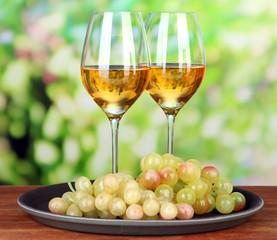 Ripe grapes and glasses of wine, on bright background