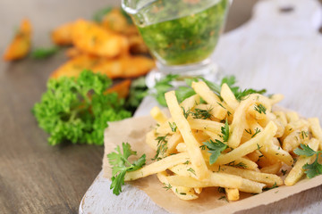 French fries on tracing paper on board on wooden table