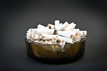 Full ashtray with butts over black