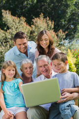 Obraz premium Multi generation family with a laptop sitting in park
