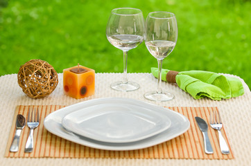 Empty plate with fork and knife against meadow. Table