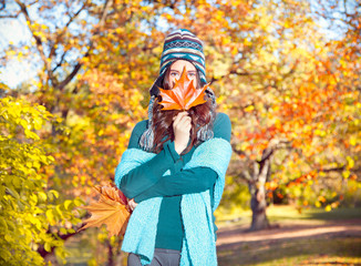 Beautiful girl with leaves on an sunny autumn-day in park