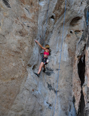 woman climbing on the rock route summer