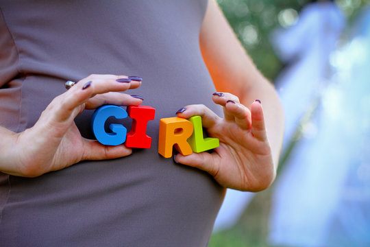 Pregnant woman holding the word girl