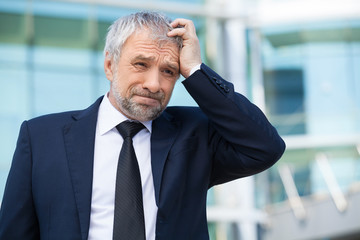 Frustrated businessman. Depressed senior man in formalwear holdi