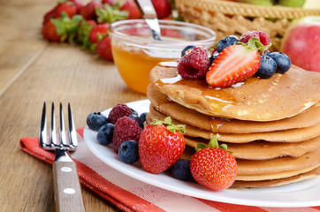 Pancakes with berries and honey closeup