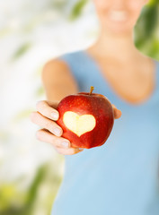 woman hand holding red apple with heart shape