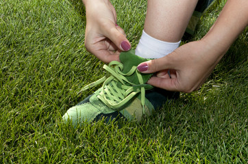 woman ties laces on green shoes