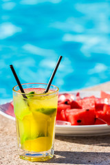 Lime cocktail in front of plate filled with red melon