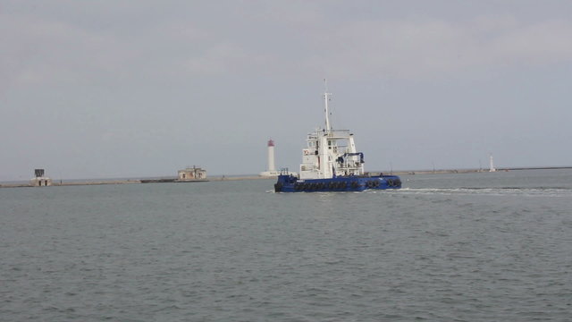 Tug swims in the bay of the port near the lighthouse