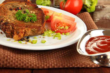 Piece of fried meat on plate on wooden table close-up