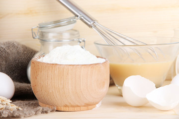 Ingredients for dough on wooden table on wooden background