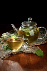 Cup and teapot of herbal tea with fresh mint flowers