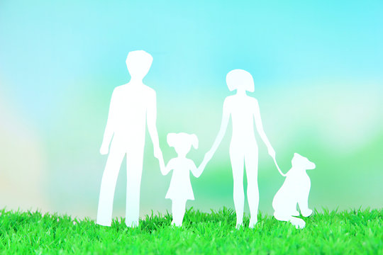 Family from paper on grass on bright background