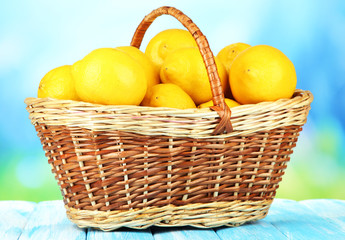 Ripe lemons in wicker basket on table on bright background