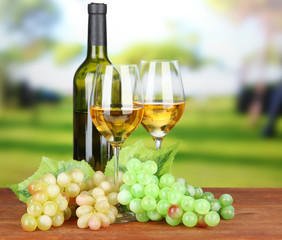 Ripe grapes, bottle and glasses of wine, on bright background