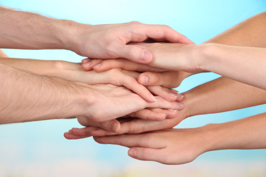 United hands on bright background. Conceptual photo of teamwork