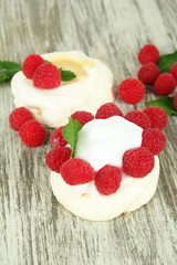 Tasty meringue cakes with berries on wooden table