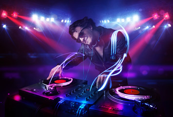 Disc jockey playing music with light beam effects on stage